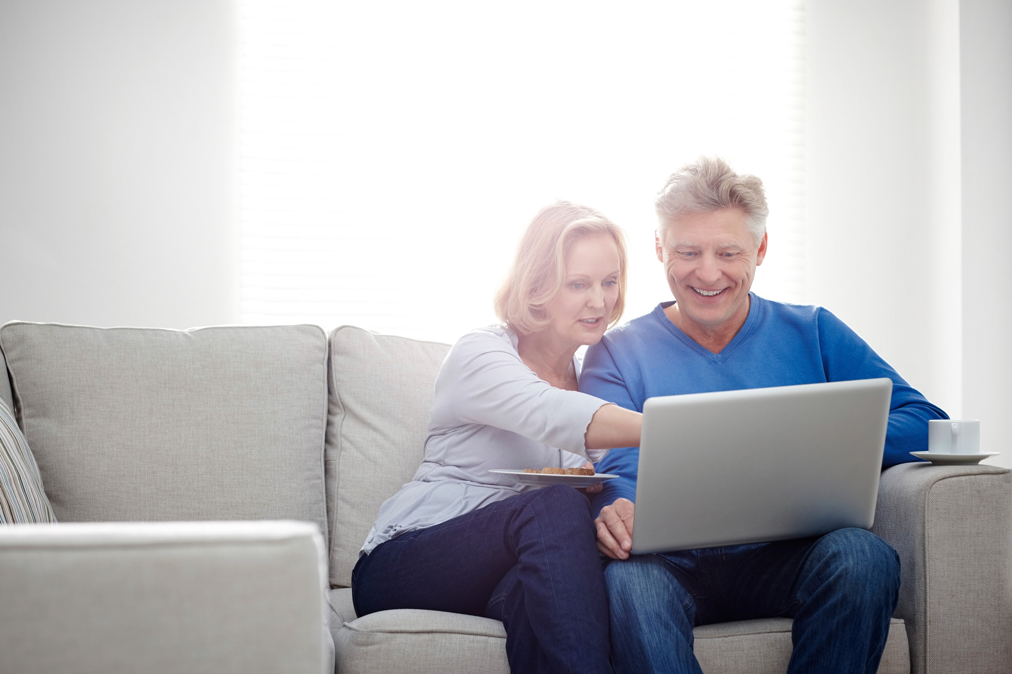 empty nester couple sitting on couch with laptop 